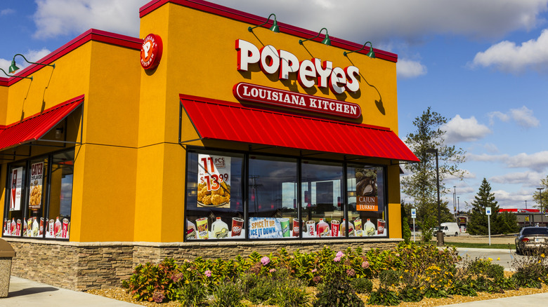 Popeyes restaurant with flowers in the front and cloudy sky in the background