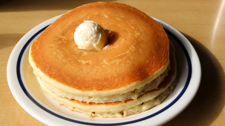 A stack of fluffy pancakes with a butter ball on top