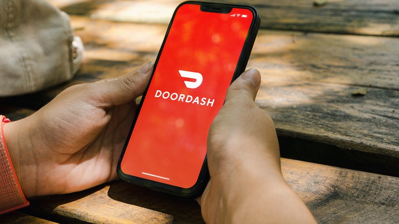 Hands holding phone with DoorDash on screen