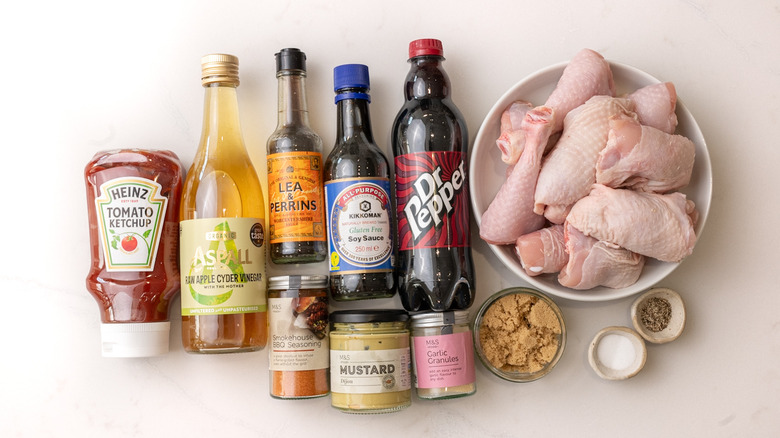Raw chicken thicks and drumsticks in bowl and other Dr Pepper barbecue chicken ingredients laid out
