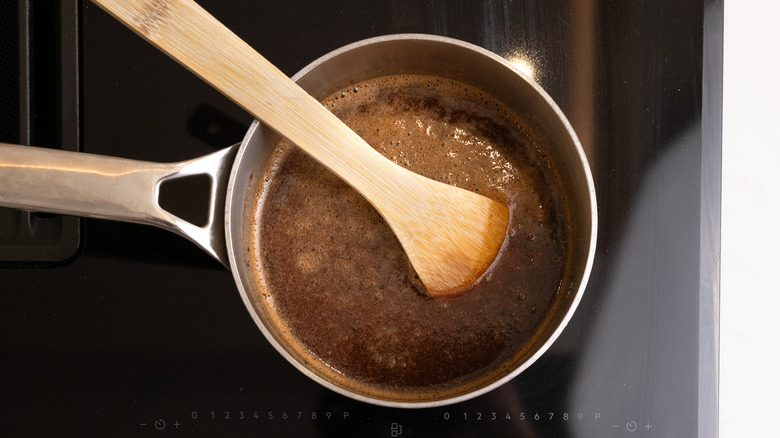 Dr Pepper barbecue sauce cooking in pot on stove with wooden spoon in pot