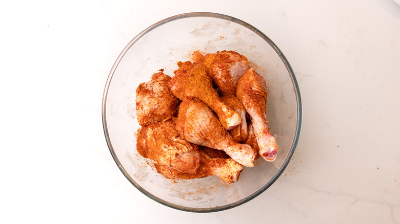 raw chicken coated with barbecue seasoning in glass bowl