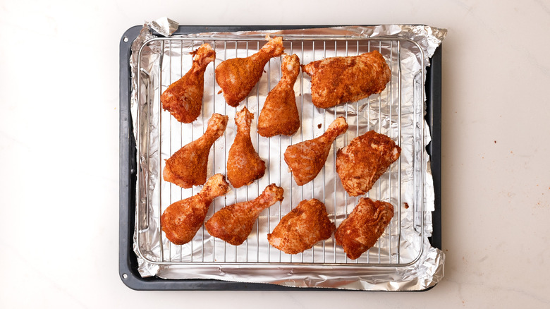 raw chicken seasoned and arranged on wire rack on top of lined baking sheet
