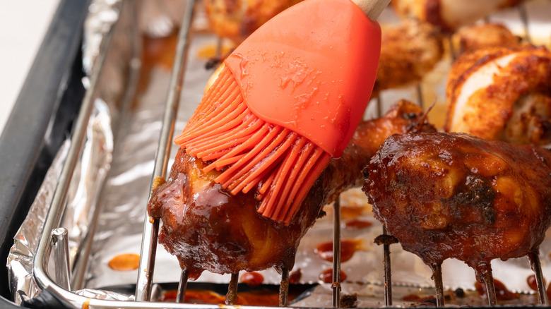 Close up of chicken getting brushed with barbecue sauce