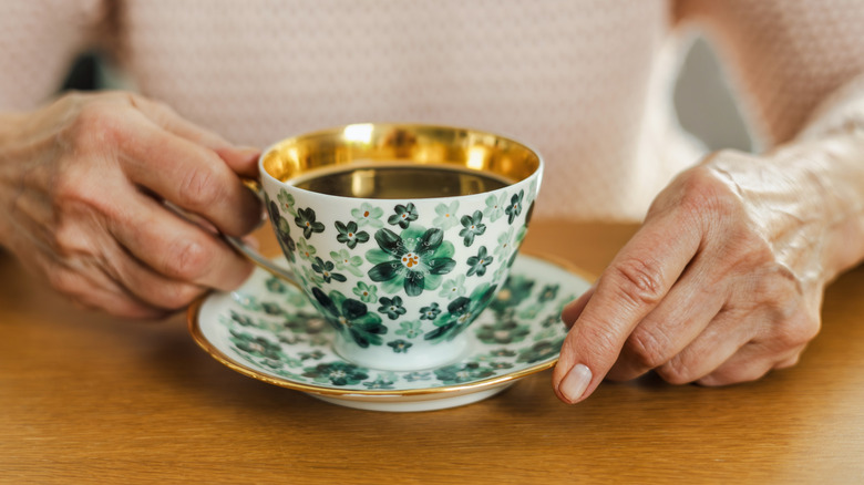 senior woman holding cup of tea or coffee