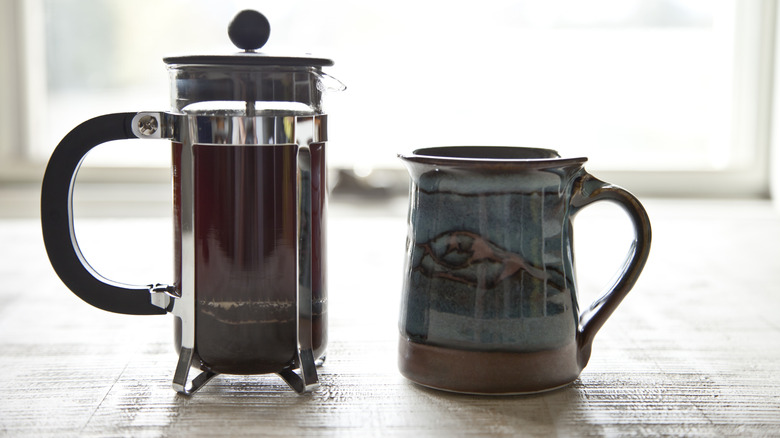 Plunged French press beside a coffee mug