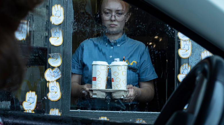 fast food employee with drinks in rain at drive-thru