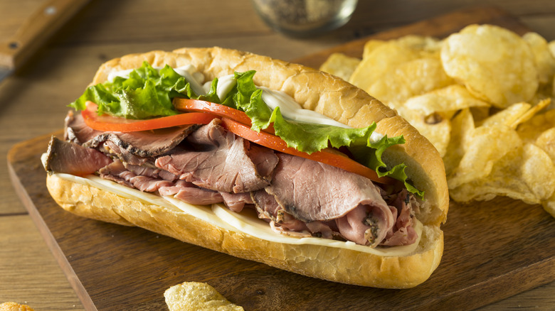 Roast beef sandwich with chips on a wooden board
