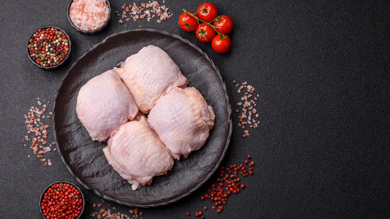 Raw chicken thighs surrounded by salt and pepper crystals