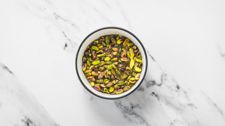 Pistachios in water in bowl.