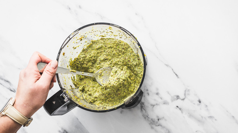 Lifting a spoonful of chia and pistachio from food processor.