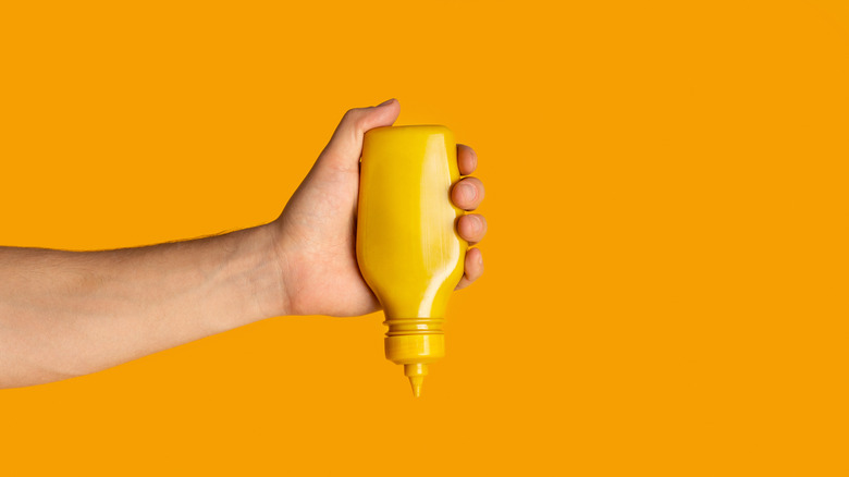 hand squeezing mustard bottle