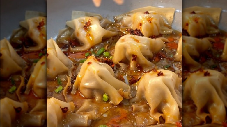 Potstickers in a pan with chili crisp and chives