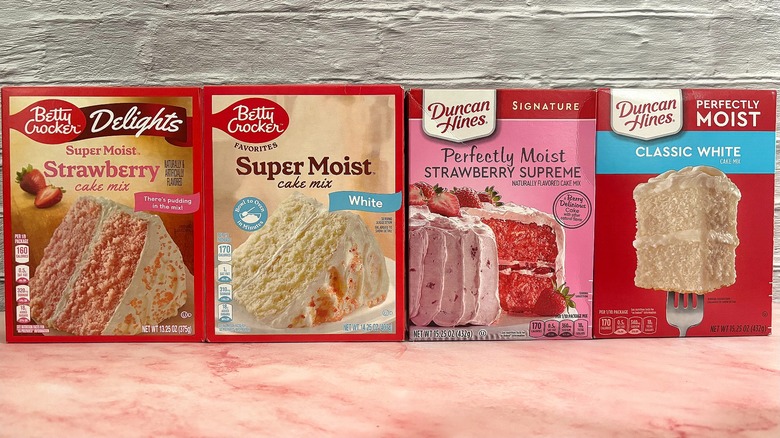 Four boxes cake mixes side-by-side on pink table