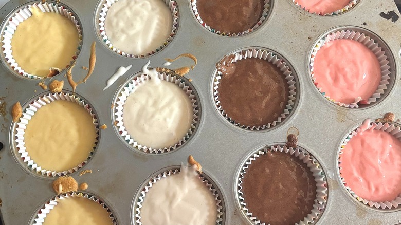 Cupcake pan with liners filled with different kinds of cupcake batter