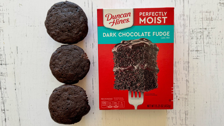 Closeup of Duncan Hines boxed chocolate cake mix and chocolate cupcakes on a table.