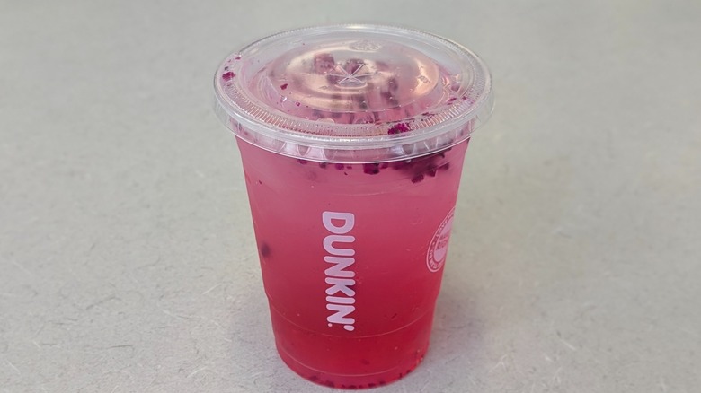 A Candy Pink Lemonade Refresher from Dunkin' on a grey table