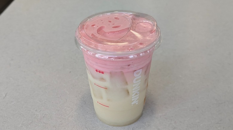 A Pink Lemon Drop Suncloud Lemonade from Dunkin' on a grey table