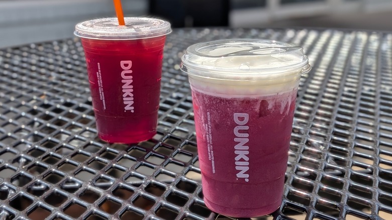 A purple Dunkin' drink with cold foam in front of another purple drink made with tea