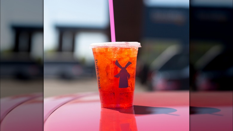 a dutch bros iced drink with a pink straw and a blurred background