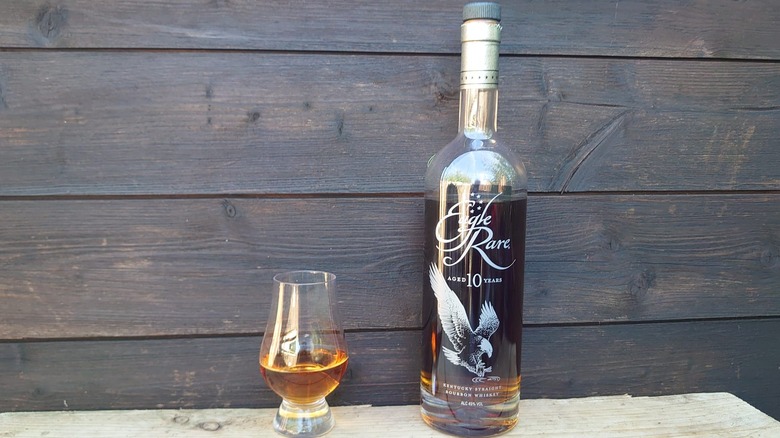 A bottle and glass of Eagle Rare 10-year in front of a wooden background