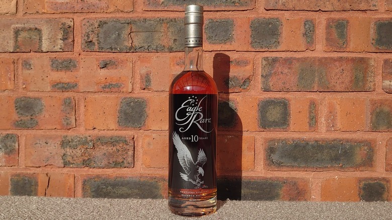 A bottle of Eagle Rare 10-year shown against a red brick wall in bright sunshine
