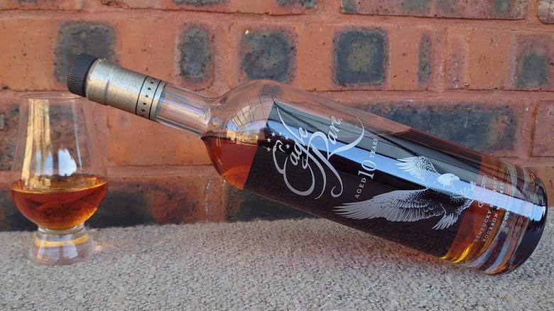 A bottle of Eagle Rare 10-year bourbon resting on a full glass of whiskey