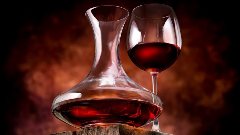 A wine decanter next to a glass of red wine
