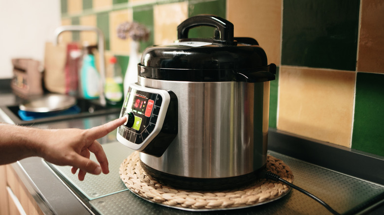 Close-up of person pushing crockpot settings button