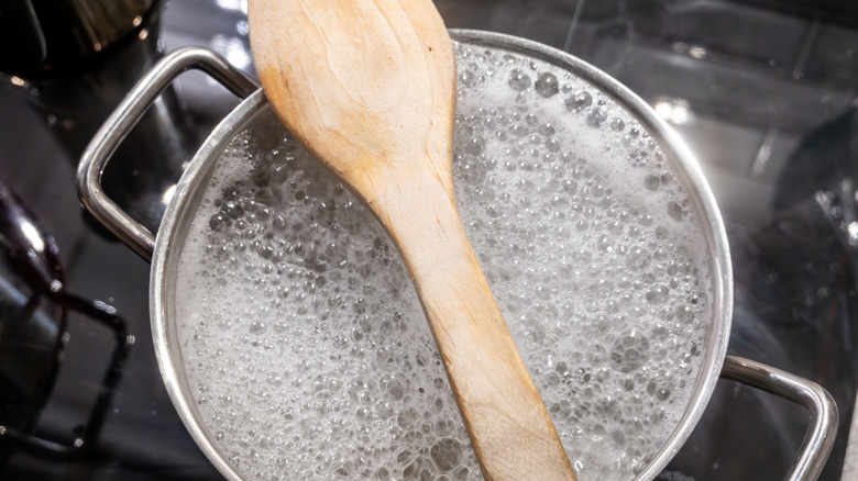 A wooden spoon placed over a pot of boiling water