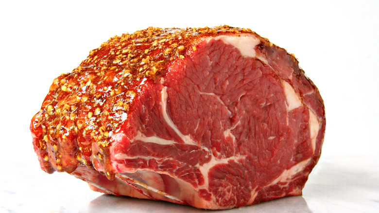 A whole raw prime rib roast covered in seasonings