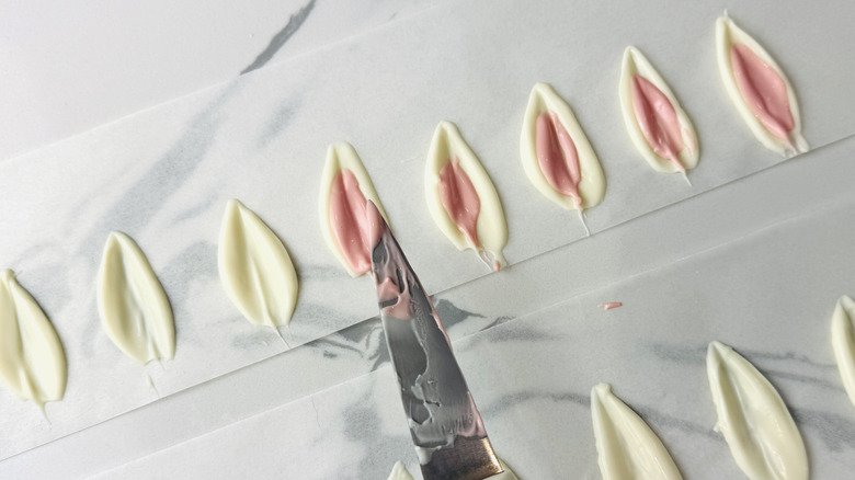 pink and white pointed oval shapes made from melted chocolate posed with a knife