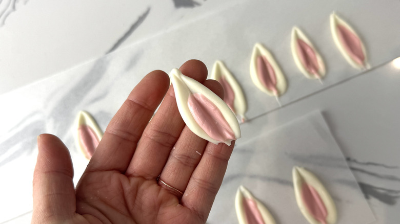 hand holding a pink and white pointed oval shape made from melted chocolate