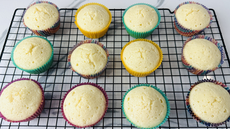 white cupcakes in paper liners sitting on a wire rack