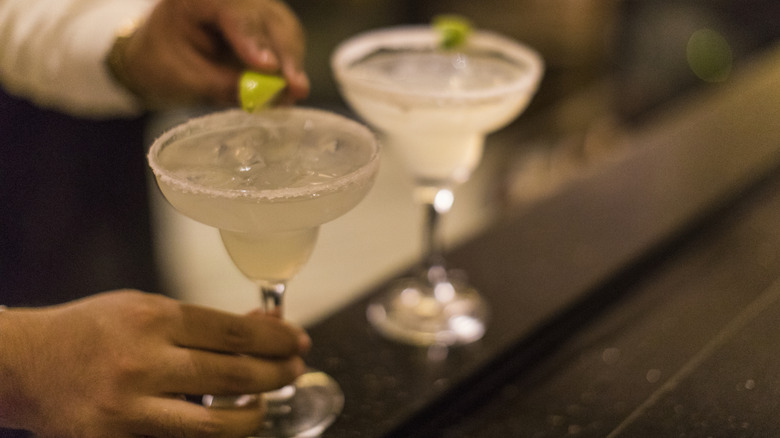 Bartender adding lime on one of two margaritas