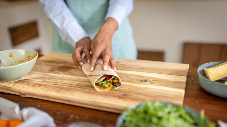 Person wrapping a burrito on kitchen counter