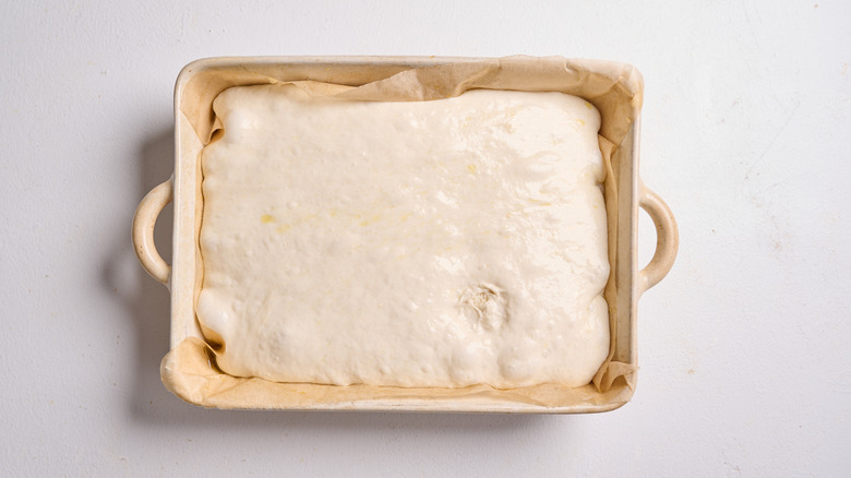 risen focaccia dough in a baking dish