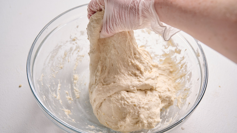 folding dough with hands in a bowl