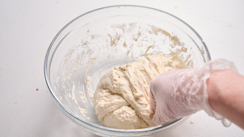 folding dough over itself in a bowl