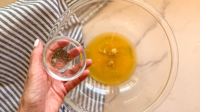 hand adding spices to bowl