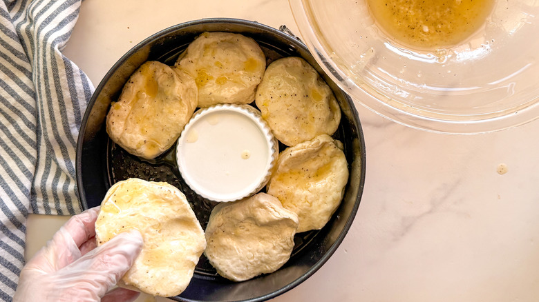 hand adding biscuit to pan