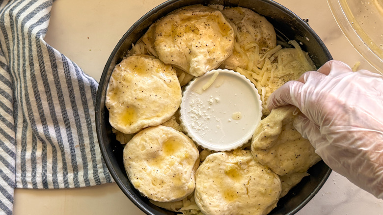 hand adding second layer of biscuits
