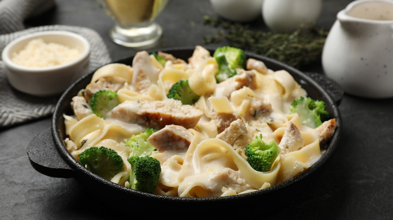 Small cast iron pan filled with pasta in creamy sauce with pieces of chicken and broccoli