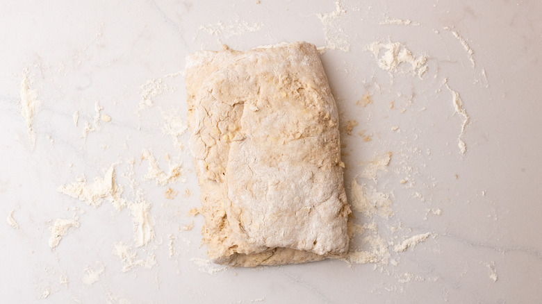folded cinnamon biscuit dough on floured surface