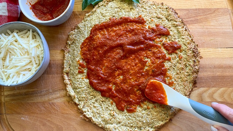 pizza crust and sauce with spatula