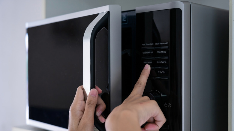 hands closing microwave oven door