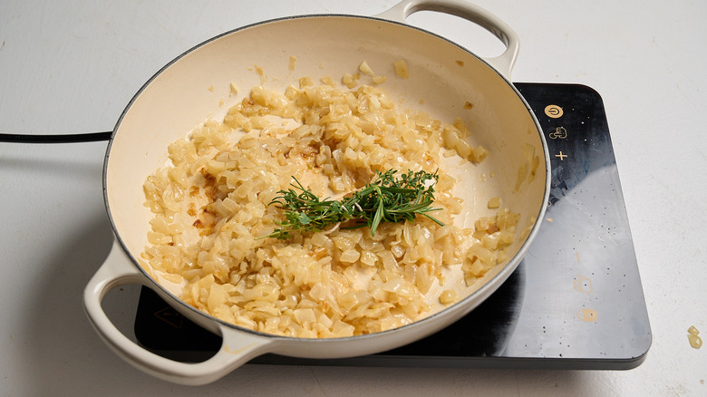 herbs and softened onions in skillet