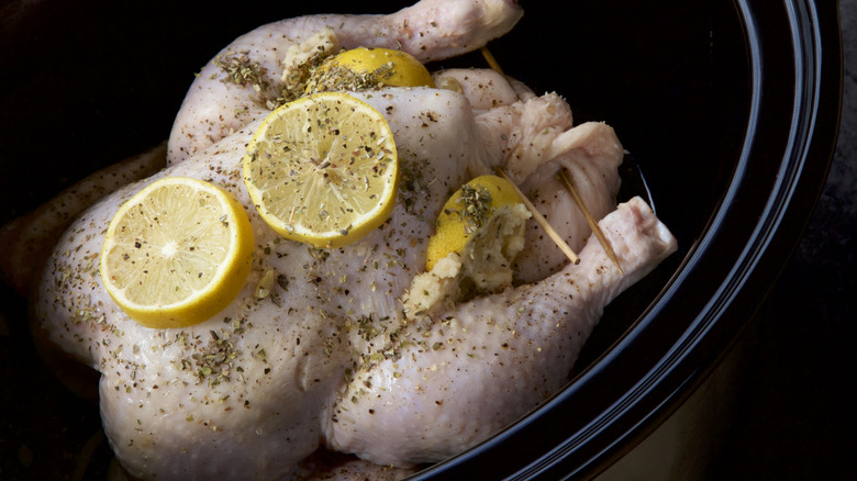 Whole chicken with herbs and lemons in slow cooker