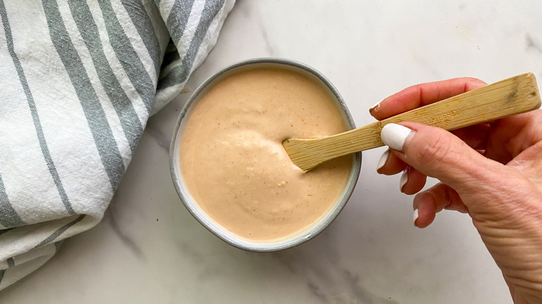 Russian dressing in small bowl with wooden spoon