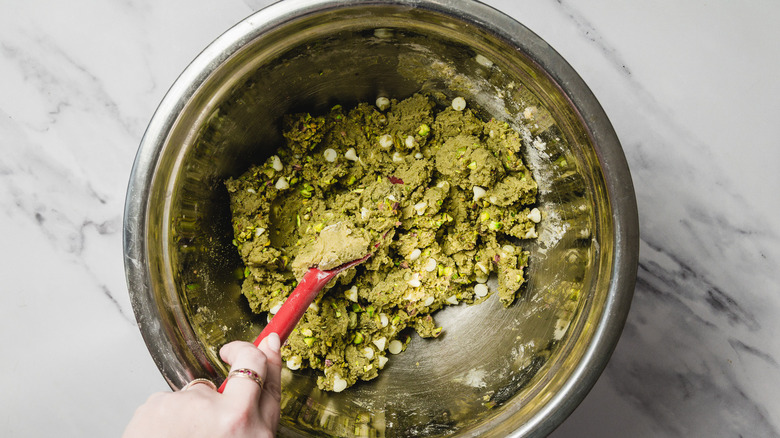 Hand mixing cookie batter with spatula in bowl